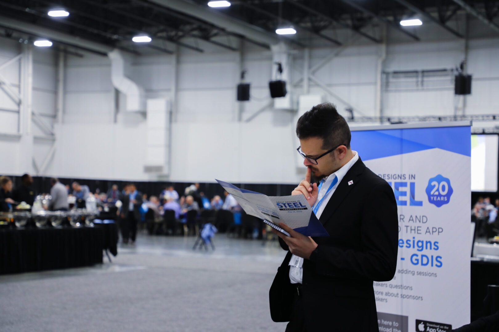 A man in black suit reading papers at an event.